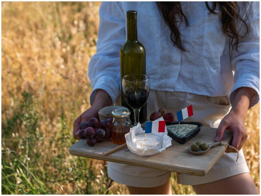 Outdoor picnic featuring wine, cheese, and French