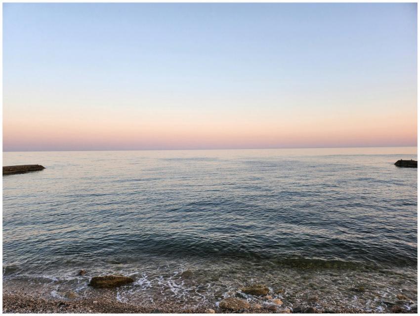 A serene coastal scene at sunset with calm waves a