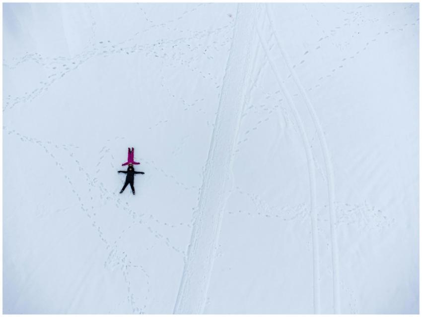 Aerial shot of two people making snow angels on a