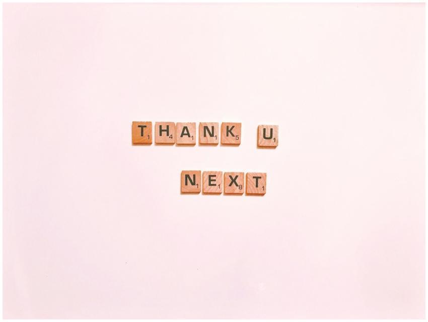 Scrabble tiles display 'Thank U Next' on a clean w