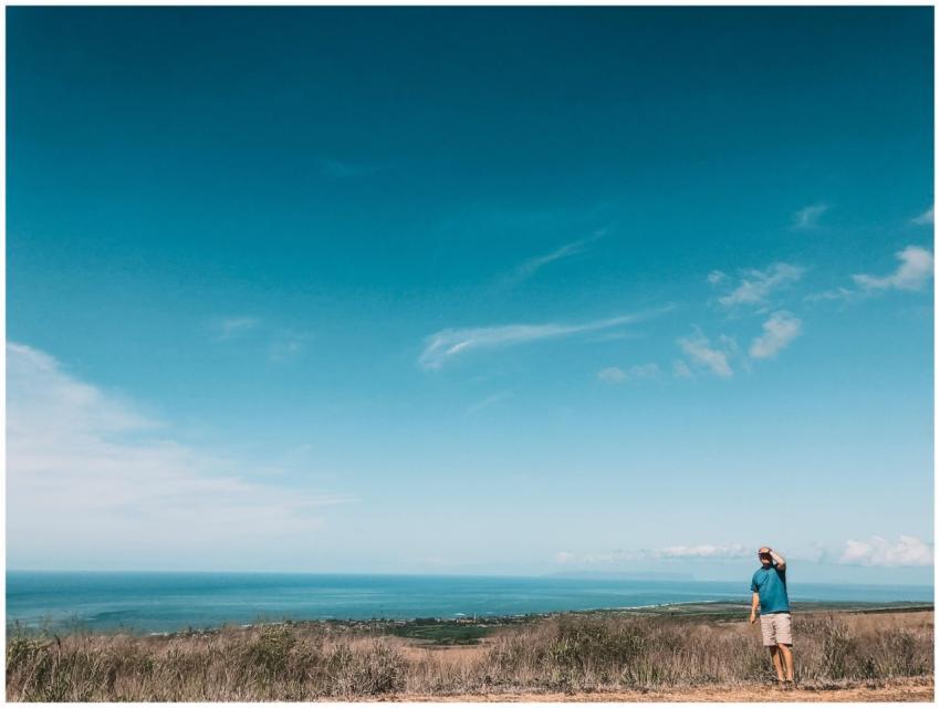 A man standing in a field overlooking a vast ocean