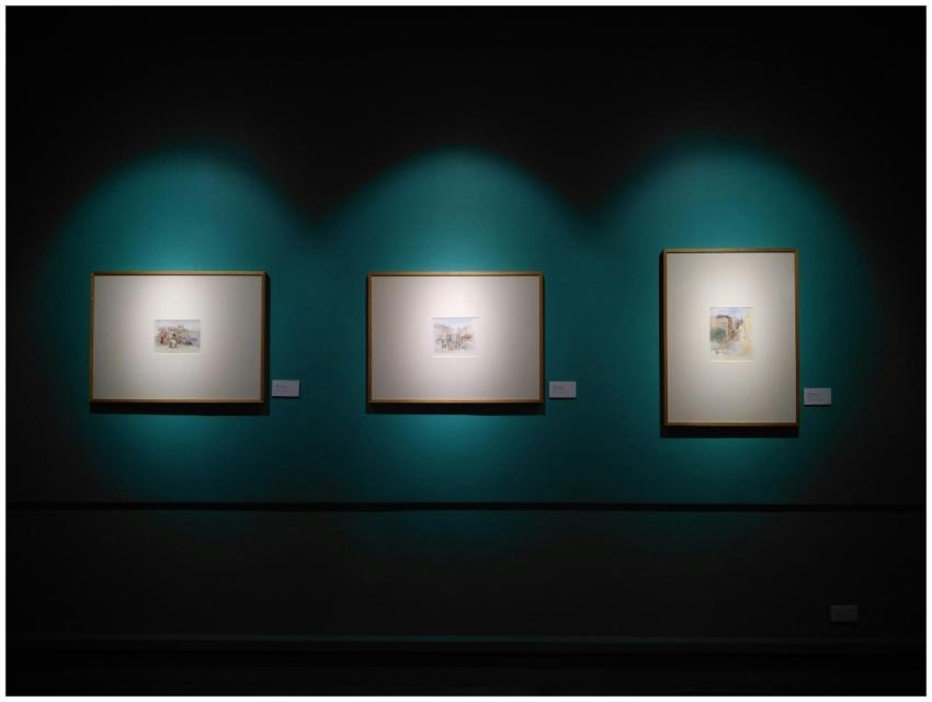 Framed artworks illuminated on a museum wall in Ma