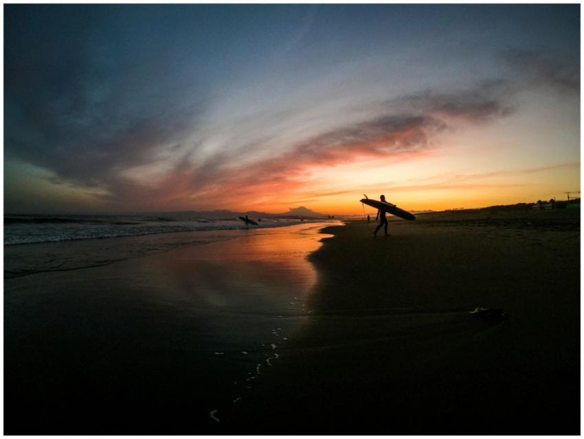 Silhouetted surfers on a Japanese beach during a v