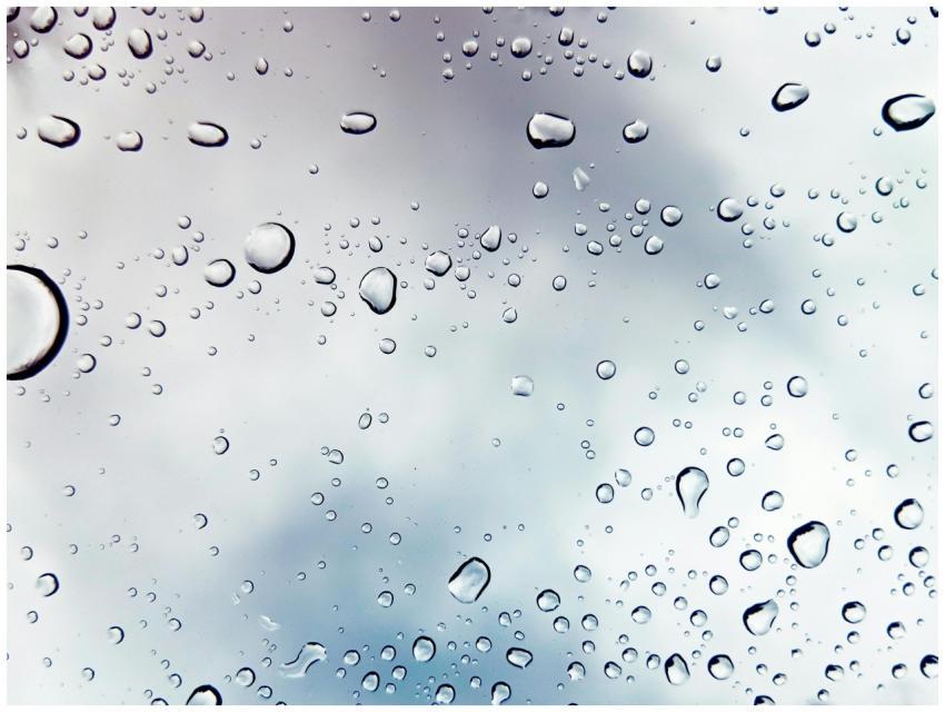 Raindrops on a window against a cloudy sky, creati