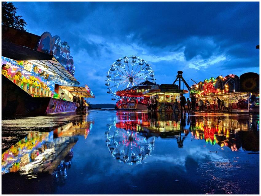 A colorful carnival at dusk reflecting on wet grou
