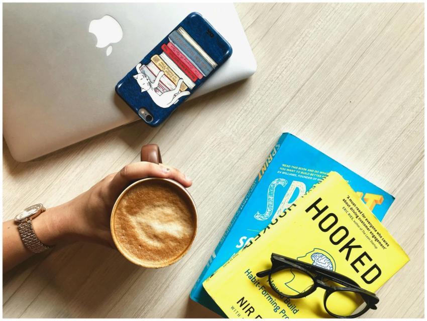 Overhead view of a workspace featuring books, coff
