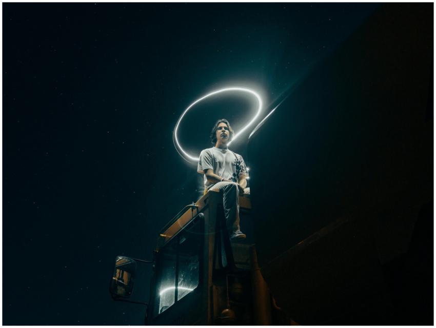 A man sits on a truck, surrounded by a light halo