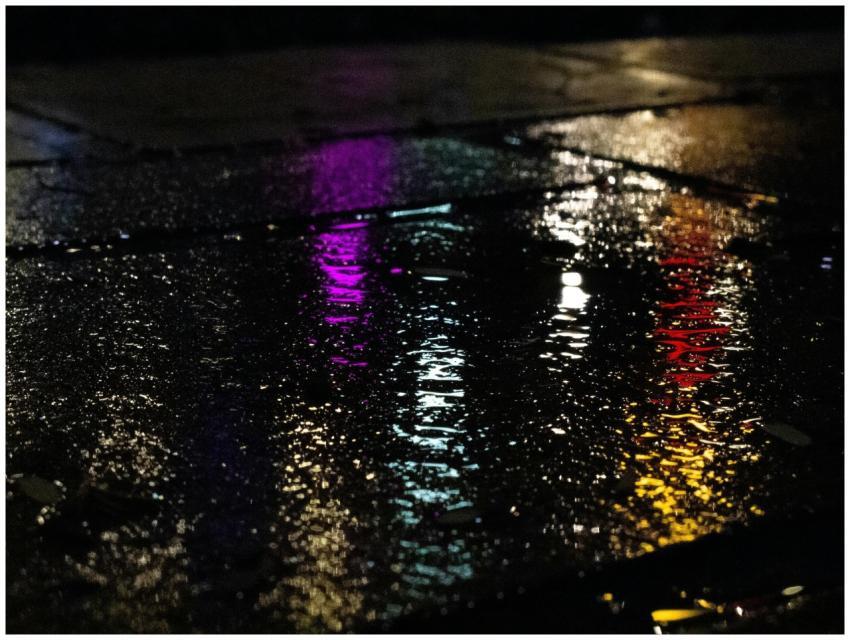 Colorful neon reflections on wet pavement capture
