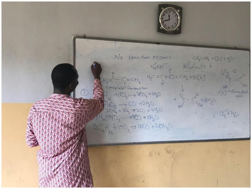 Male teacher writing chemical equations on a class