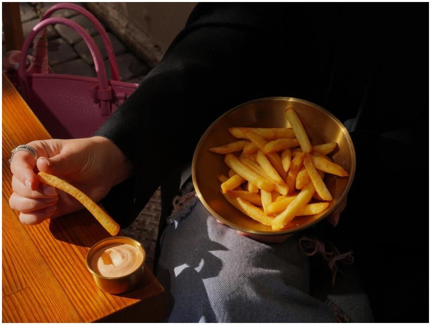 Hand holding french fry, bowl of fries, dipping sa