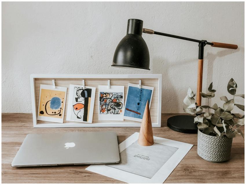 Cozy workspace featuring art prints, laptop, lamp,