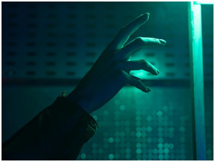A close-up of a hand reaching out in a dimly lit e