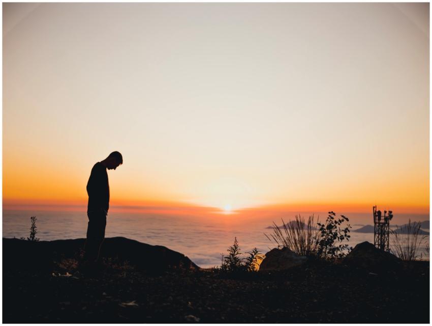 A person silhouetted against a vibrant sunset on a