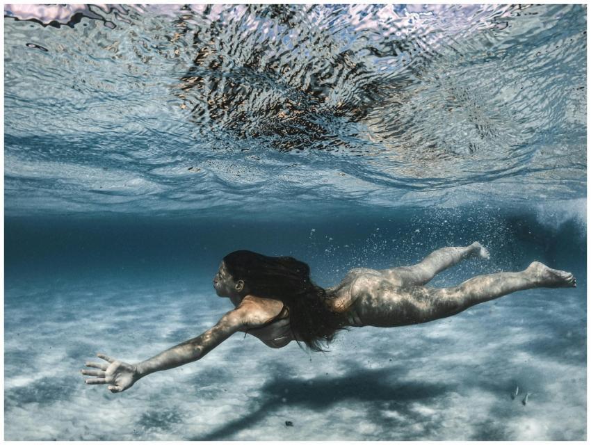 An Asian woman swims gracefully underwater, showca