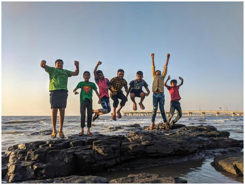 Group of kids joyfully jumping on rocks by the sea