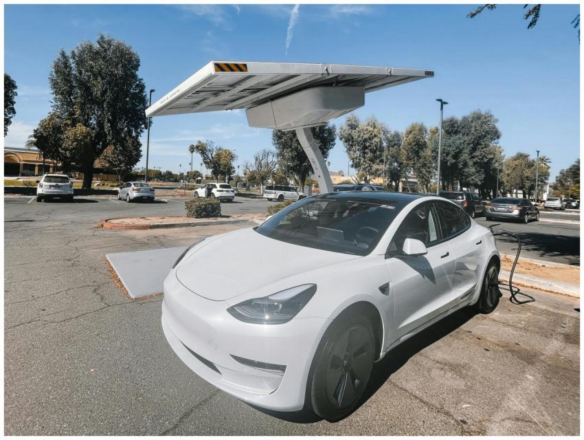 Modern white electric car charging under solar pan