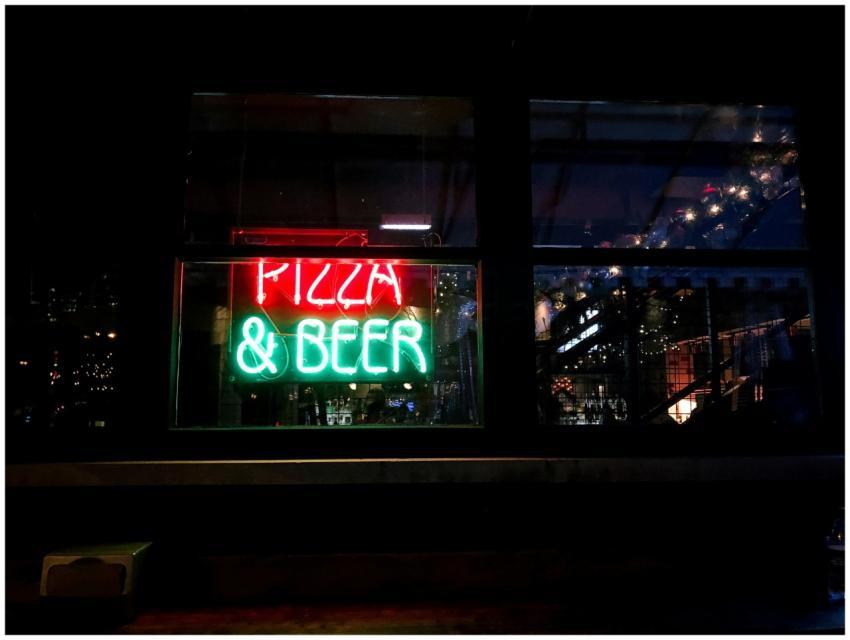 Vibrant neon sign for pizza & beer illuminates a C