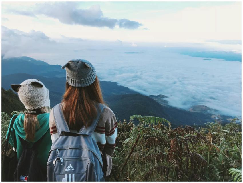 Two women with backpacks enjoy a scenic mountain v