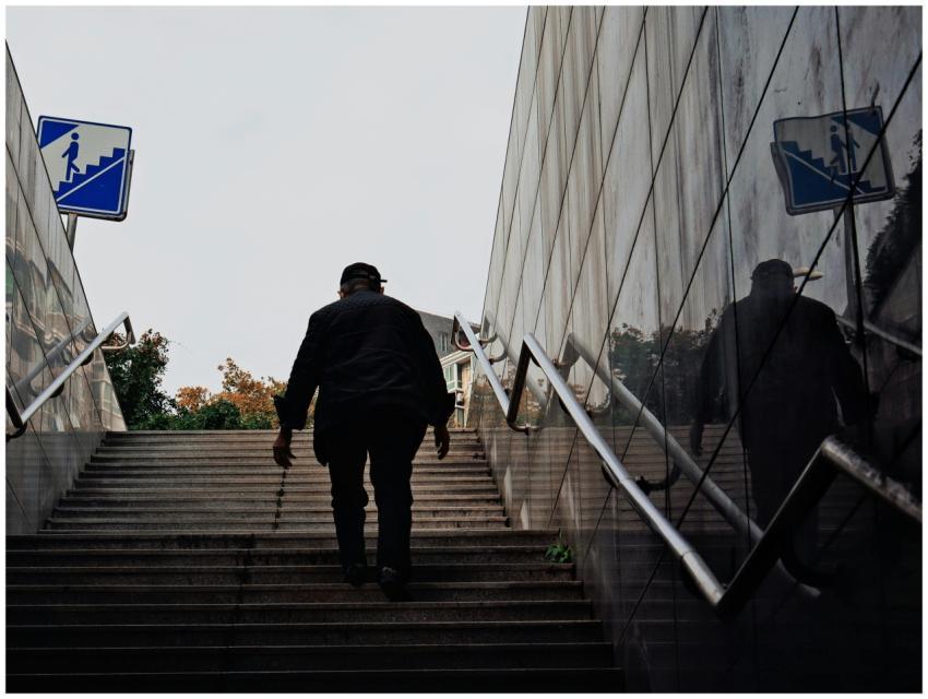 A person climbing outdoor subway stairs with refle