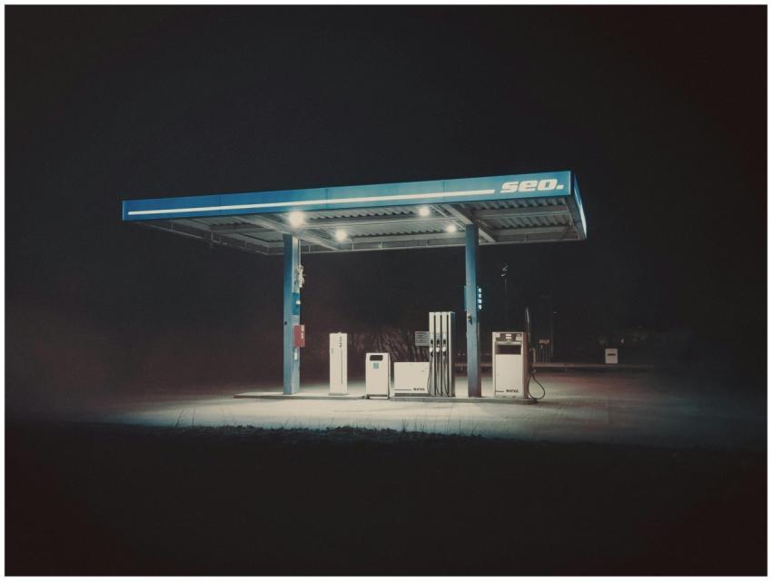 A dimly lit gas station under a dark sky evokes a