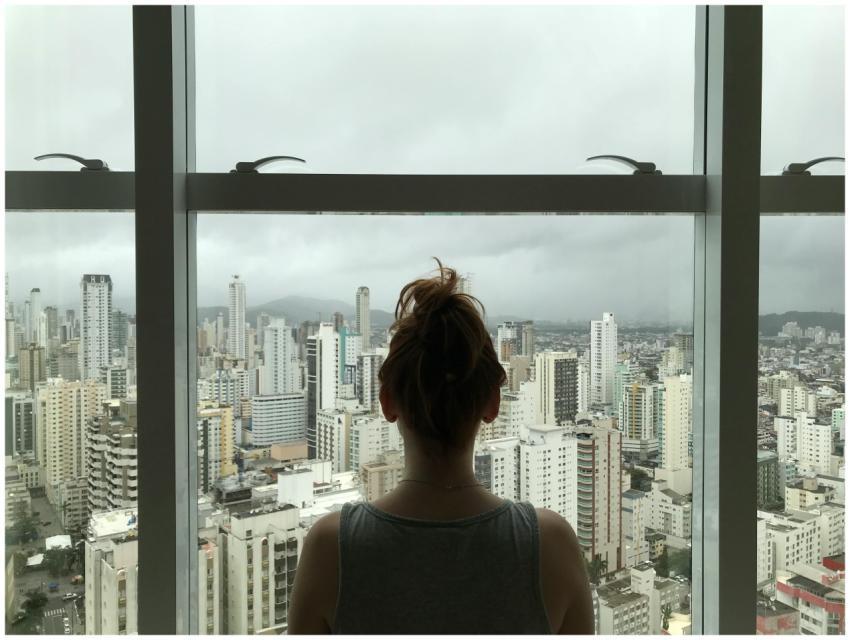 A woman gazing at a cloudy city skyline through a