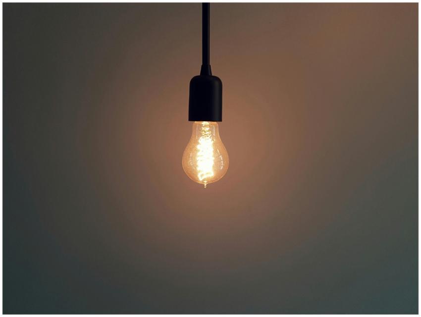 Simple illuminated light bulb hanging in a dark ro