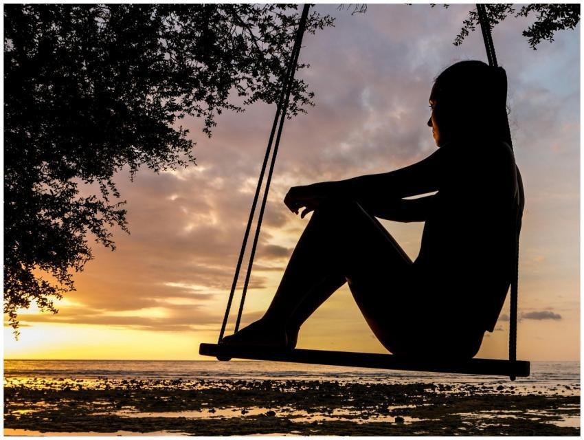 A serene sunset silhouette of a woman sitting on a