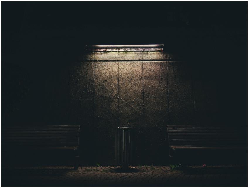 Dark urban night scene with benches and a fluoresc