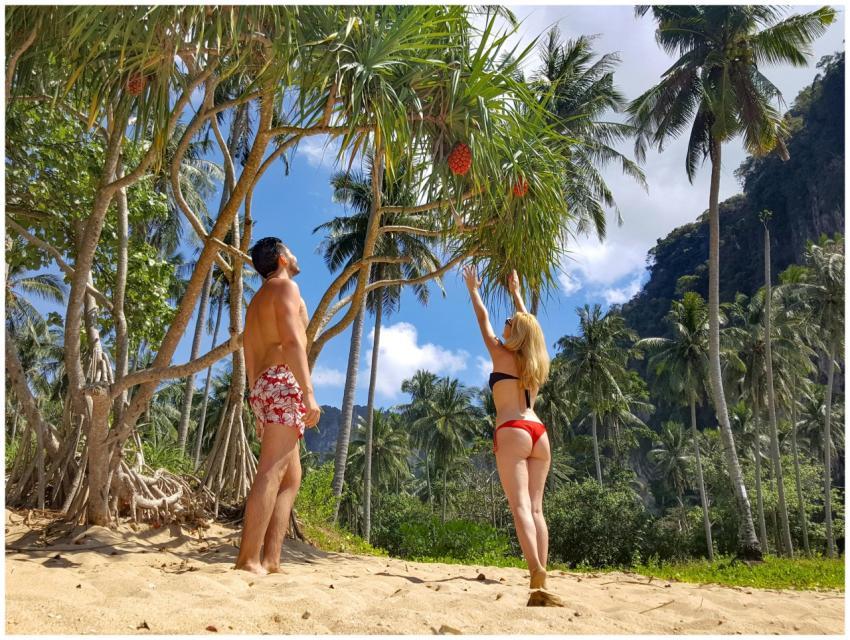 Young couple in swimwear relaxing under palm trees