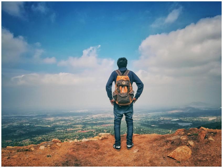 A man stands on a mountain edge appreciating the e