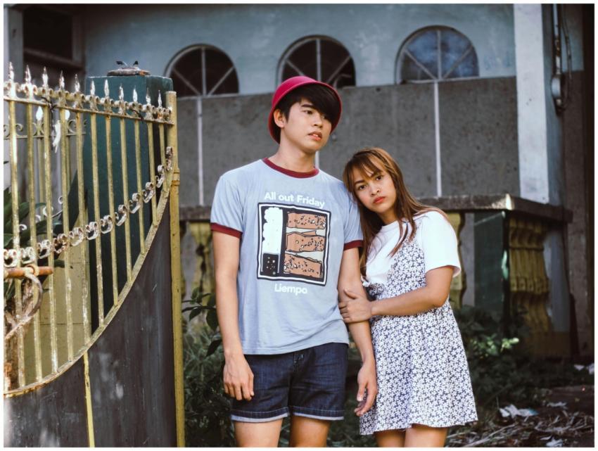 An Asian couple stands outdoors in casual fashion