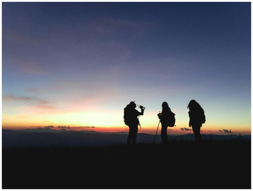 Group of hikers silhouetted against a vibrant suns