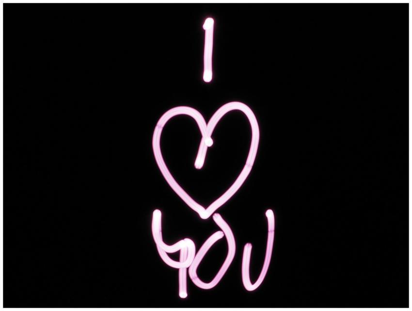 Bright pink light painting of 'I Love You' on a bl