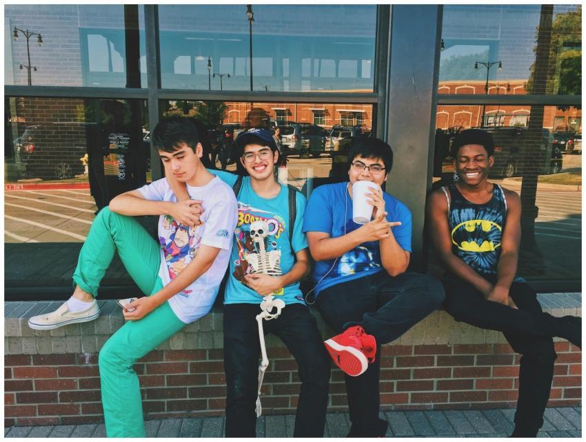 Group of teenage friends sitting outdoors, smiling