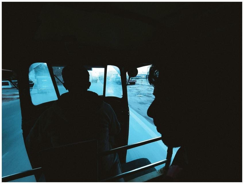 Silhouettes of men inside a moving auto rickshaw o