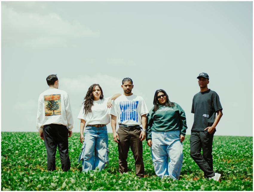 Five young adults stand confidently in a green fie