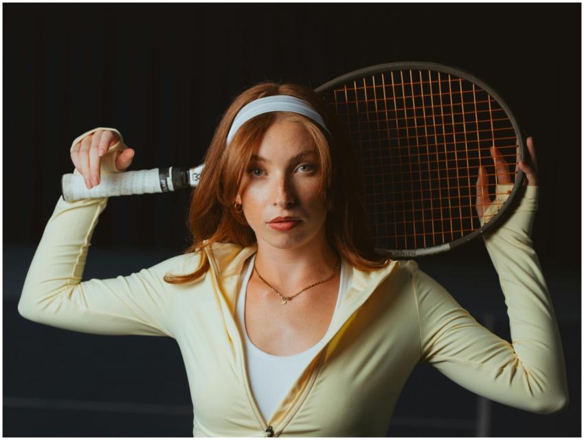 Confident female tennis player holding a racket, r