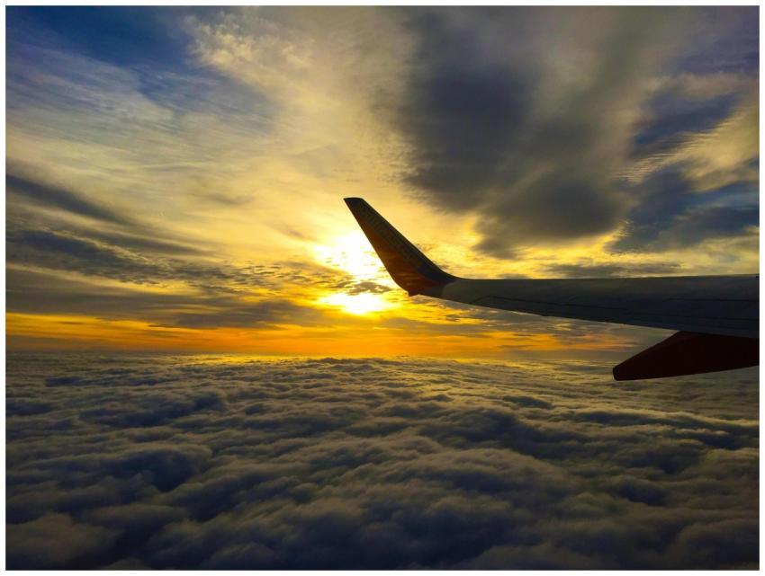 A breathtaking view of an airplane wing above clou
