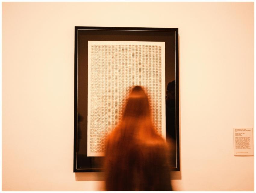 A blurred figure views artwork in a London museum,