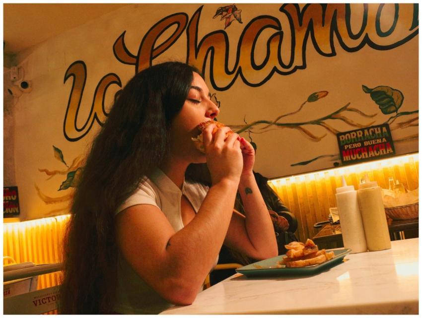 Woman eating a burger at a lively diner with color