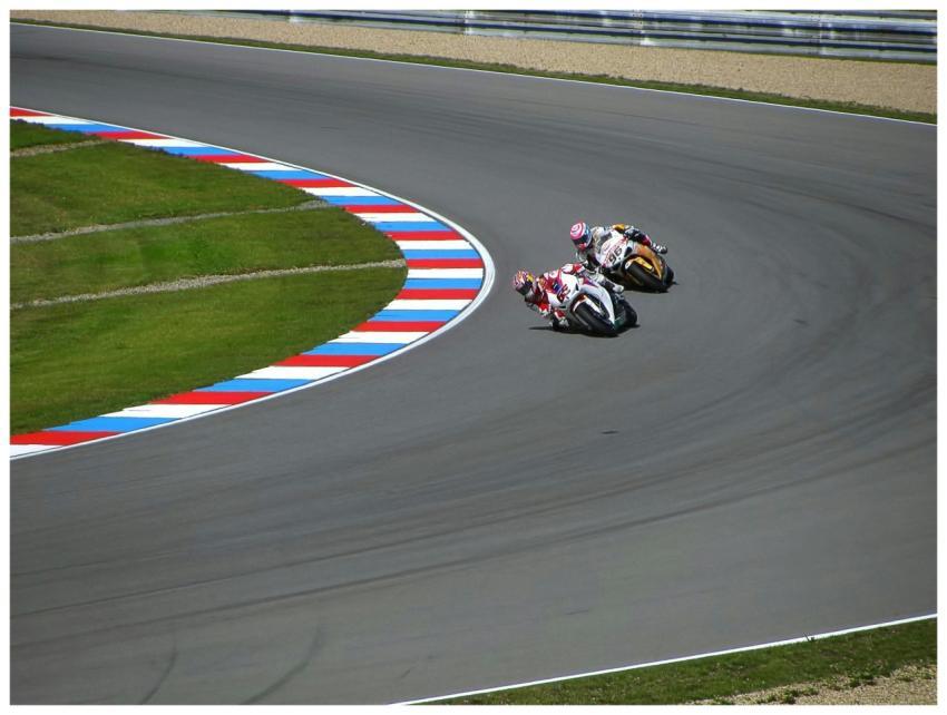 Two motorcyclists racing on a vibrant, curved race