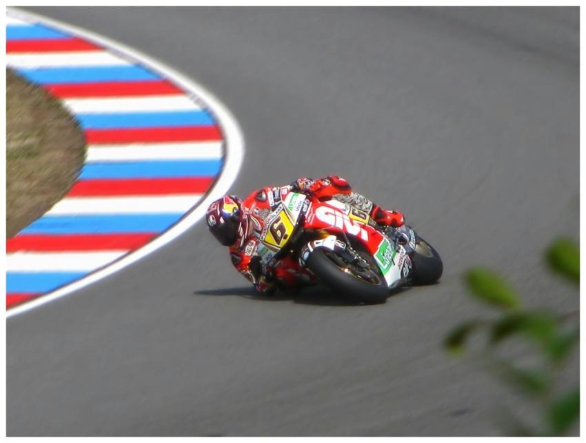 Motorcycle racer leans into a sharp curve on a hig