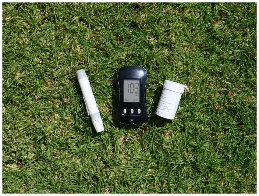 Closeup of blood glucose meter with tools on grass