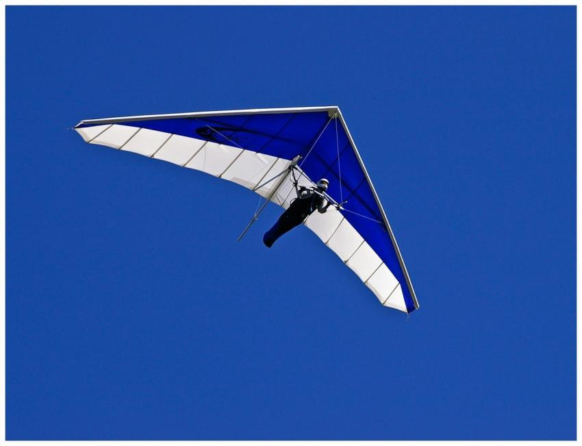 Person hang gliding through a vivid blue sky, show