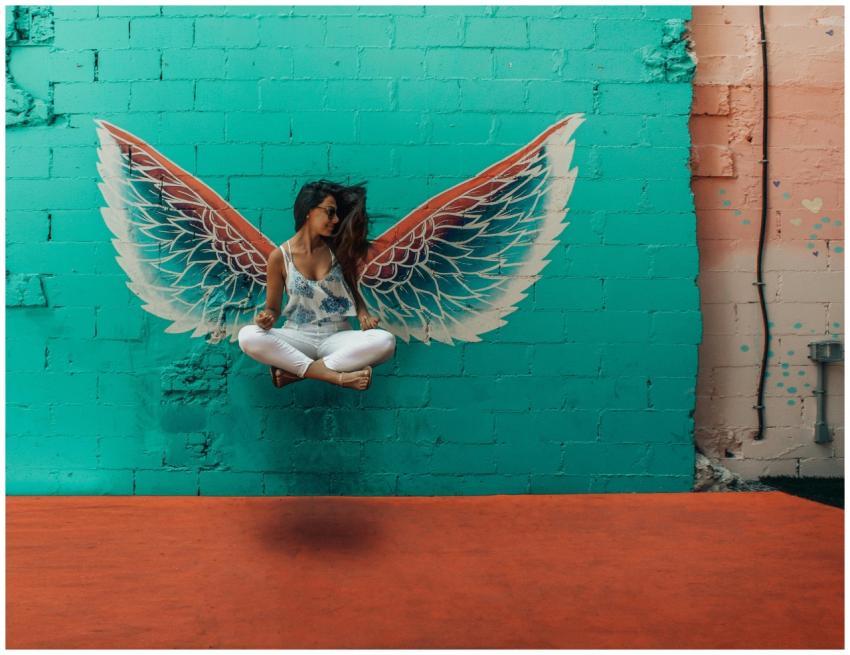 Woman posing in front of vibrant mural with angel