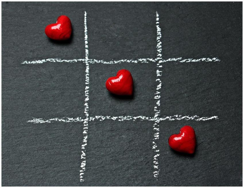 Tic tac toe board on black surface with red heart
