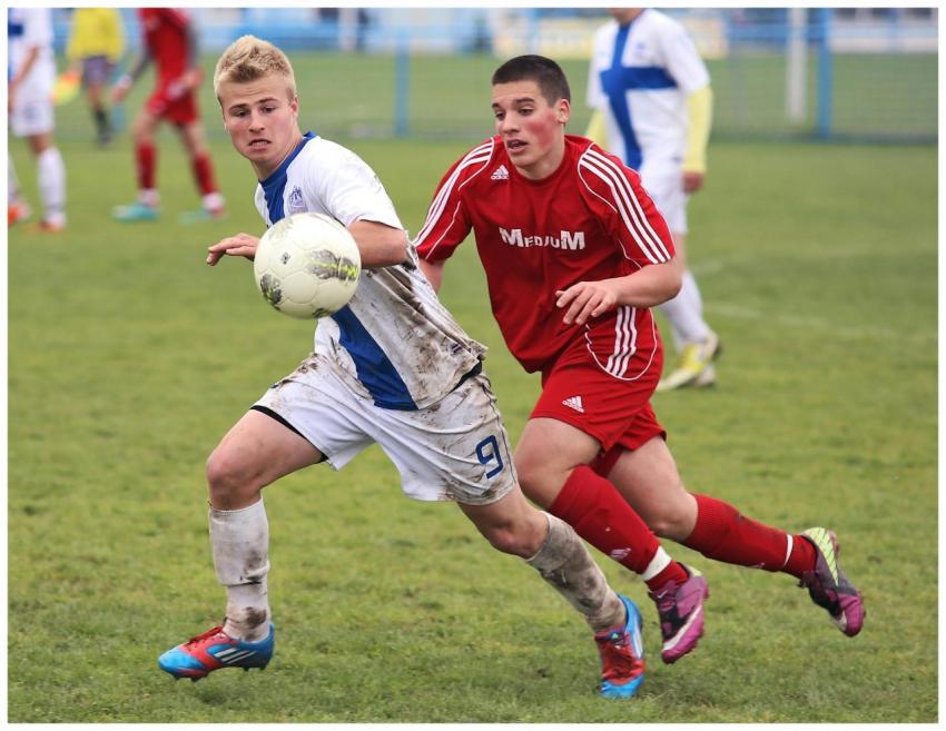 Two teenage soccer players competing fiercely on a