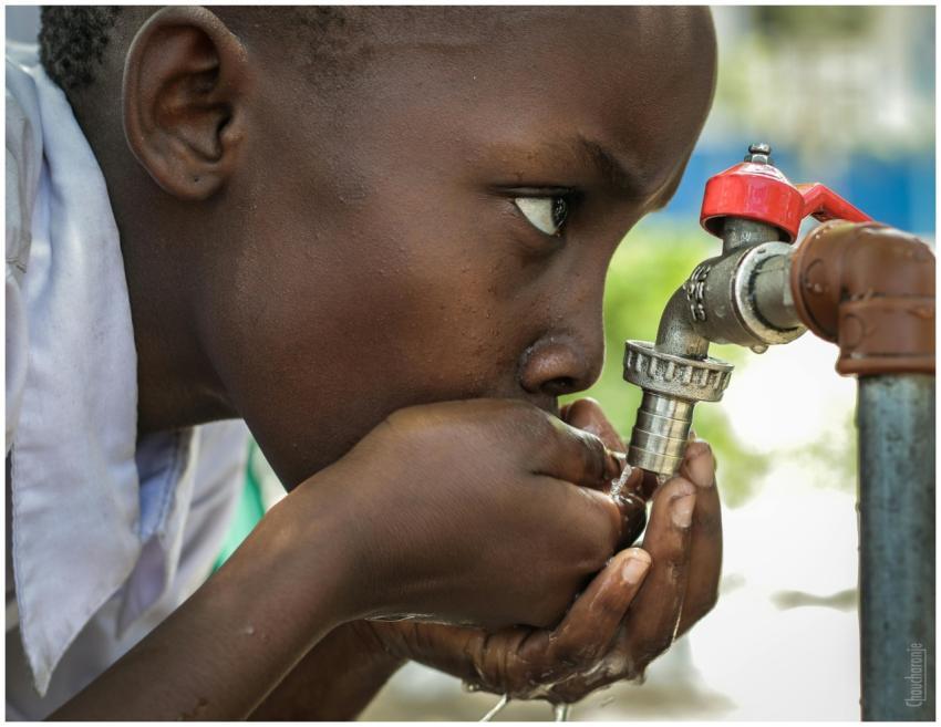 Close-up of a child drinking water from a faucet i