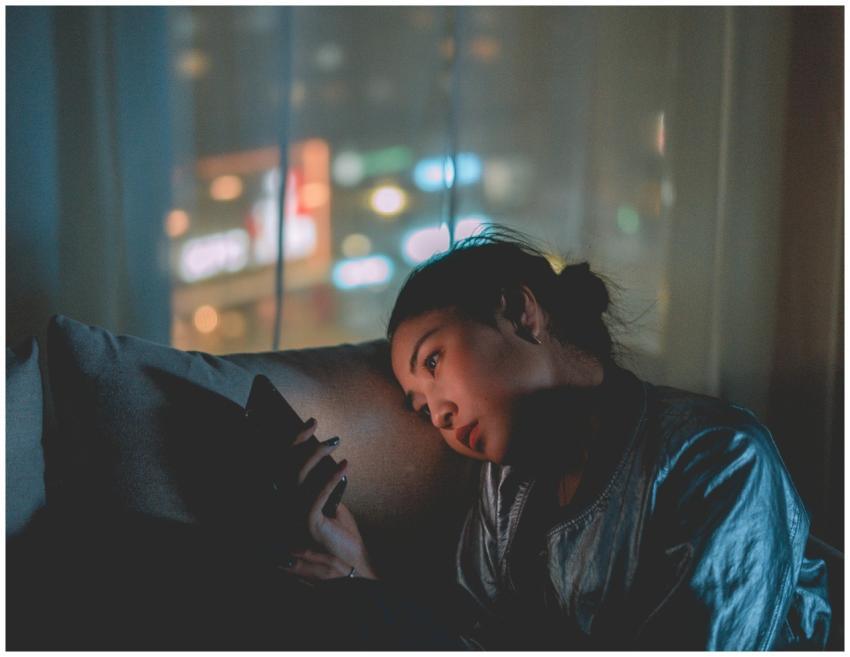 A woman looking at her mobile phone at night with