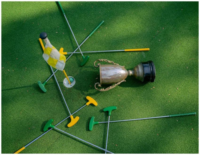 Mini golf setup with colorful putters, a cup, and